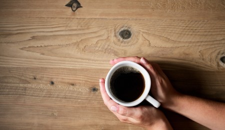 Hands holding white coffee mug