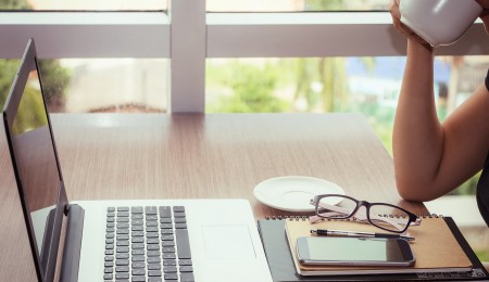 Woman drinking coffee and typing on laptop computer